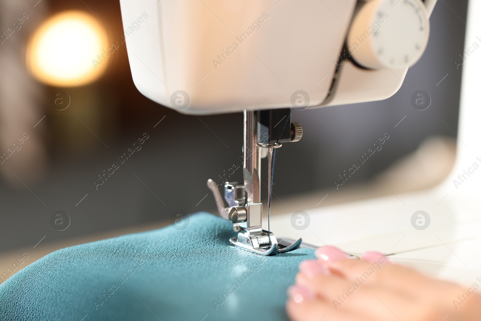 Woman working with sewing machine on blurred background, macro view Photo of Woman working with sewing machine on blurred background, macro view