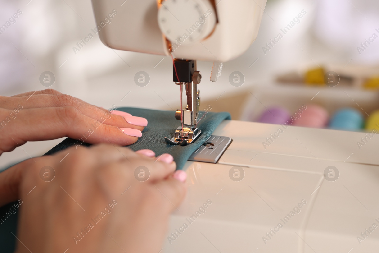 Woman working with sewing machine and fabric in workshop, closeup Photo of Woman working with sewing machine and fabric in workshop, closeup