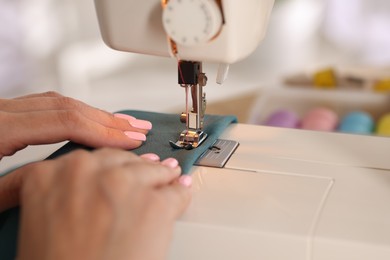 Photo of Woman working with sewing machine and fabric in workshop, closeup