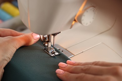 Photo of Woman working with sewing machine and fabric in workshop, closeup