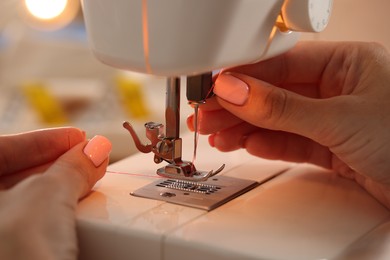 Photo of Woman working with sewing machine in workshop, closeup