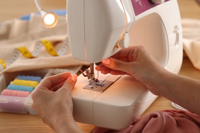 Photo of Woman working with sewing machine in workshop, closeup