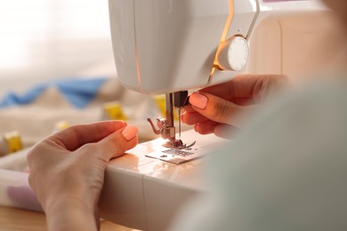 Photo of Woman working with sewing machine in workshop, closeup