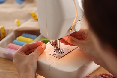 Photo of Woman working with sewing machine in workshop, closeup
