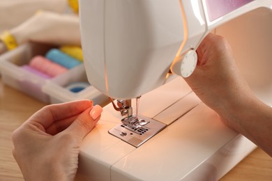 Photo of Woman working with sewing machine in workshop, closeup