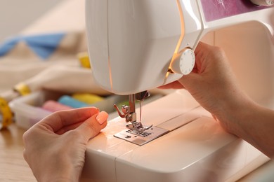 Photo of Woman working with sewing machine in workshop, closeup