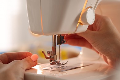Photo of Woman working with sewing machine in workshop, closeup
