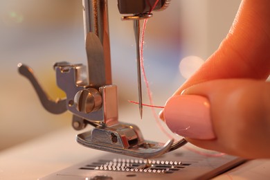 Photo of Woman working with sewing machine in workshop, closeup