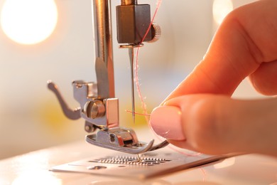 Photo of Woman working with sewing machine in workshop, closeup