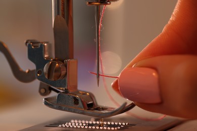 Photo of Woman working with sewing machine in workshop, closeup