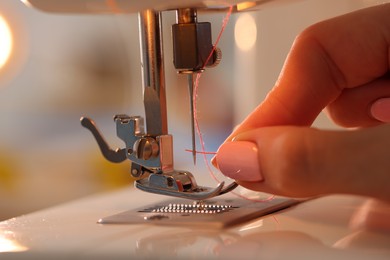 Photo of Woman working with sewing machine in workshop, closeup
