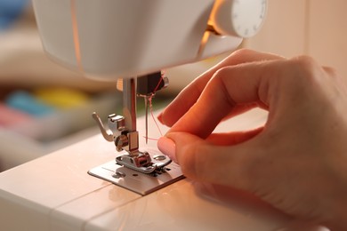 Photo of Woman working with sewing machine in workshop, closeup