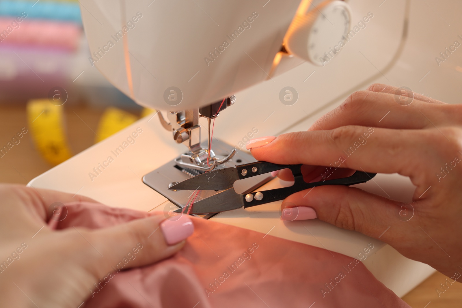 Woman working with sewing machine and fabric in workshop, closeup Photo of Woman working with sewing machine and fabric in workshop, closeup