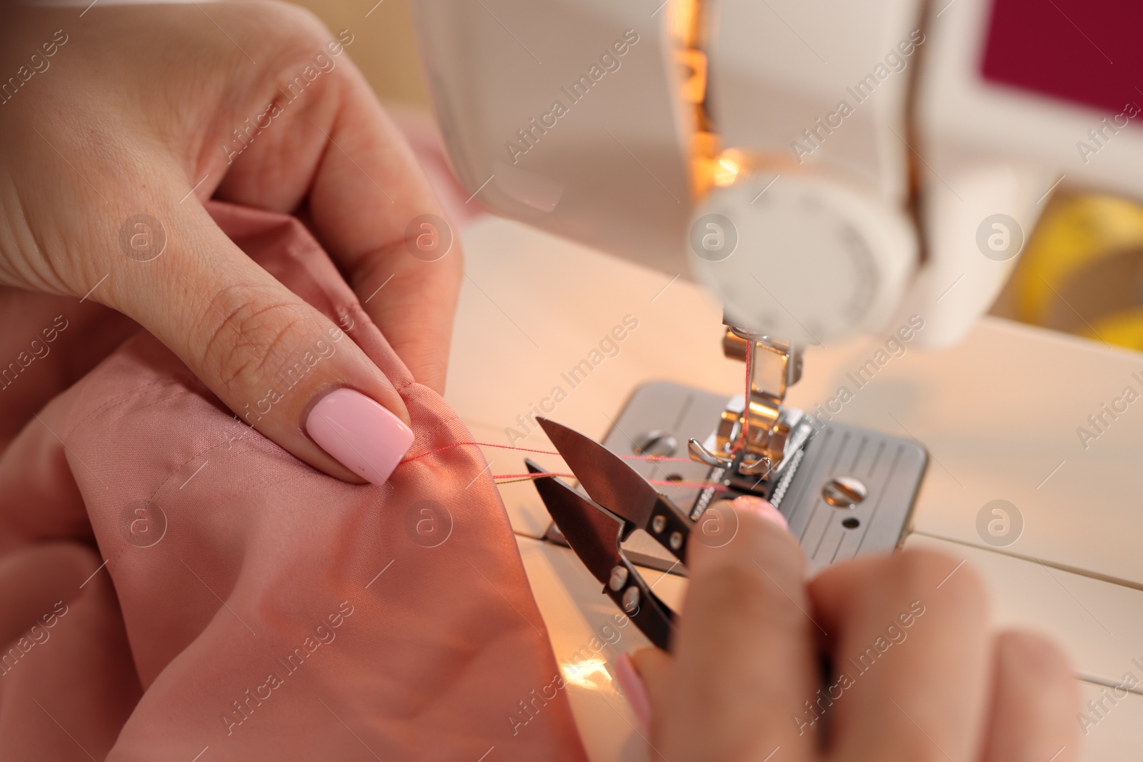 Woman working with sewing machine and fabric in workshop, closeup Photo of Woman working with sewing machine and fabric in workshop, closeup