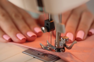 Photo of Woman working with sewing machine and fabric in workshop, closeup
