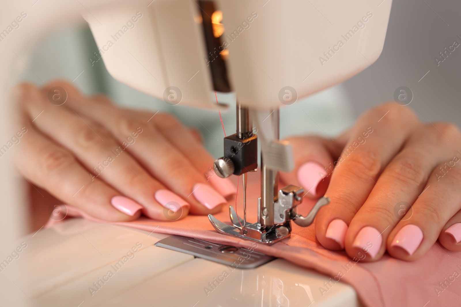 Woman working with sewing machine and fabric in workshop, closeup Photo of Woman working with sewing machine and fabric in workshop, closeup