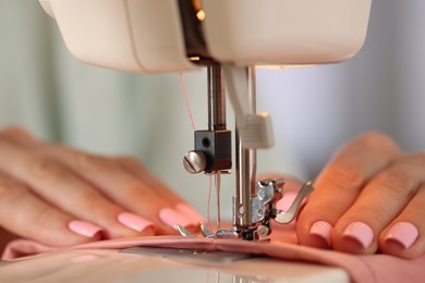 Photo of Woman working with sewing machine and fabric in workshop, closeup