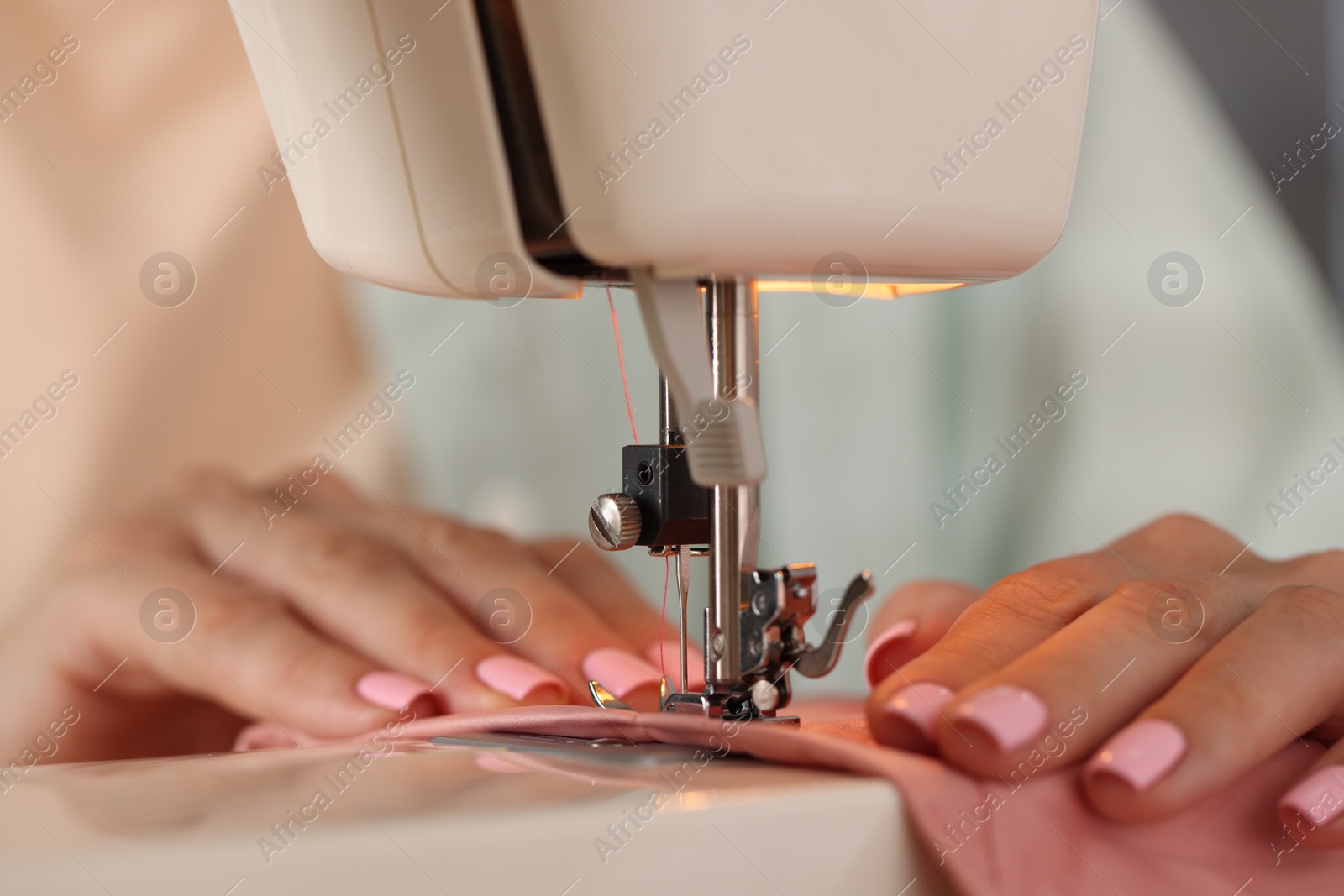 Woman working with sewing machine and fabric in workshop, closeup Photo of Woman working with sewing machine and fabric in workshop, closeup