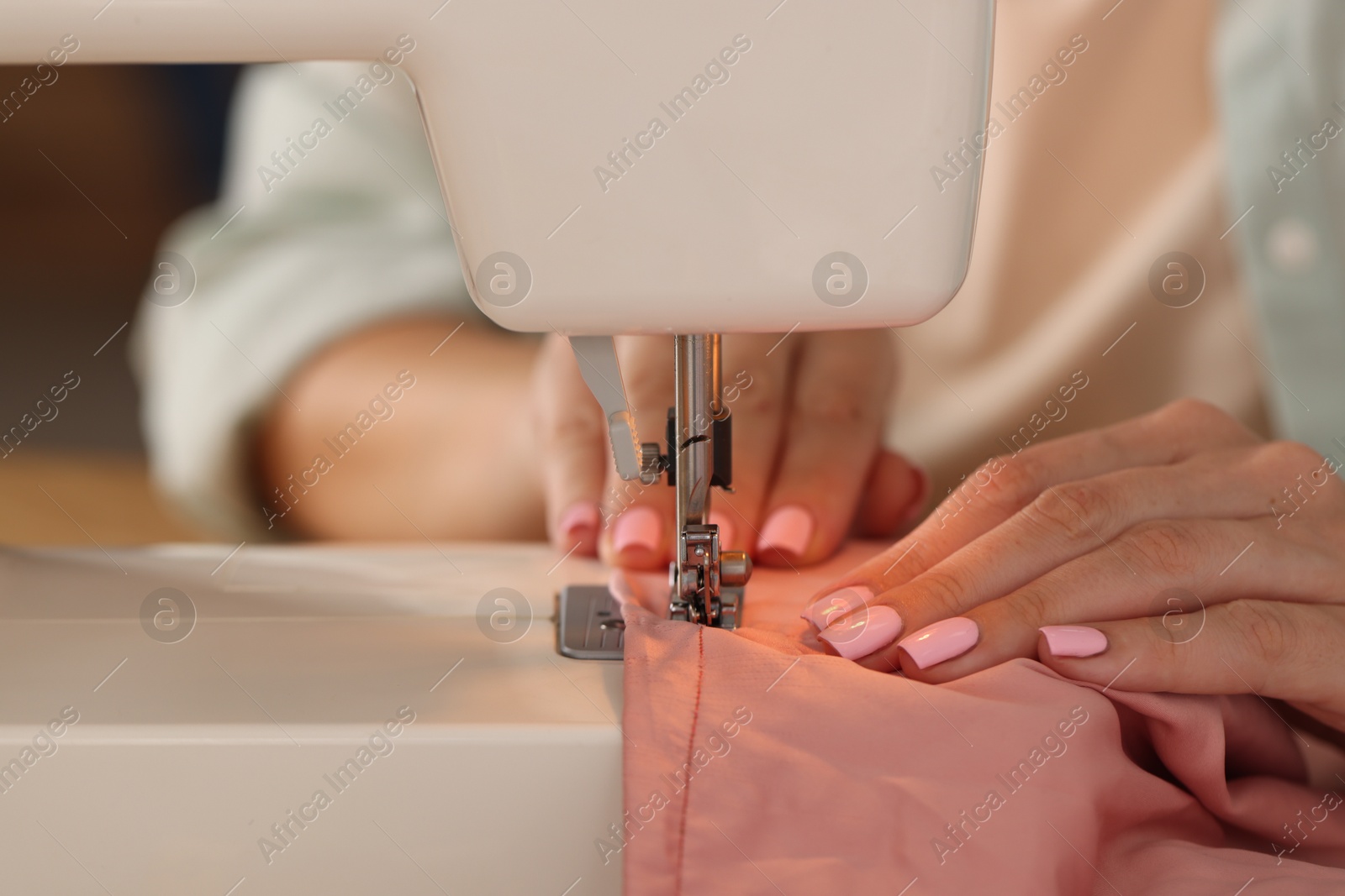 Woman working with sewing machine and fabric in workshop, closeup Photo of Woman working with sewing machine and fabric in workshop, closeup