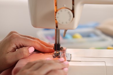 Photo of Woman working with sewing machine and fabric in workshop, closeup