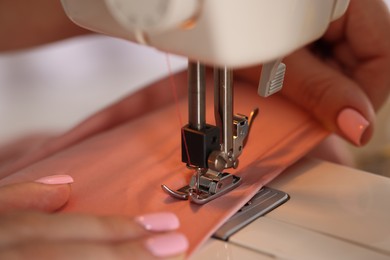 Photo of Woman working with sewing machine and fabric in workshop, closeup