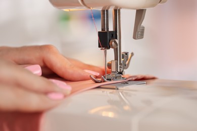 Photo of Woman working with sewing machine and fabric in workshop, closeup