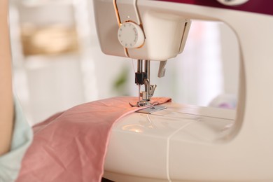 Photo of Closeup view of sewing machine with thread and pink fabric