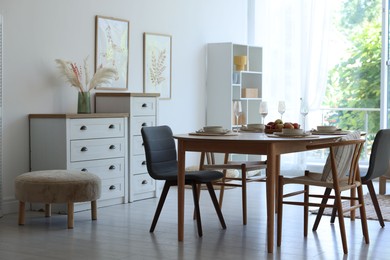 Photo of Beautiful table setting, chairs and decor in dining room. Interior design