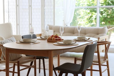 Photo of Beautiful table setting, chairs and decor in dining room. Interior design