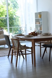 Photo of Beautiful table setting, chairs and decor in dining room. Interior design