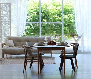 Photo of Beautiful table setting, chairs and decor in dining room. Interior design