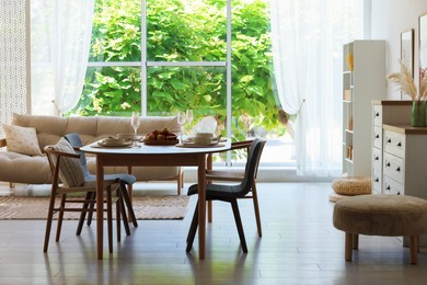 Photo of Beautiful table setting, chairs and decor in dining room. Interior design