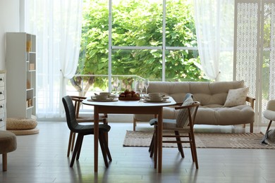 Photo of Beautiful table setting, chairs and decor in dining room. Interior design