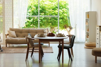 Photo of Beautiful table setting, chairs and decor in dining room. Interior design