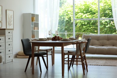 Photo of Beautiful table setting, chairs and decor in dining room. Interior design