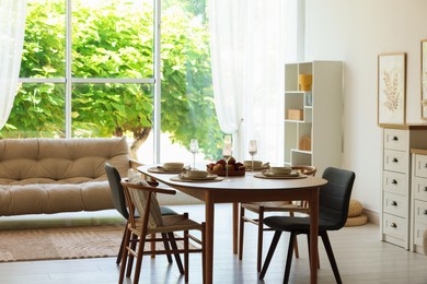 Photo of Beautiful table setting, chairs and decor in dining room. Interior design