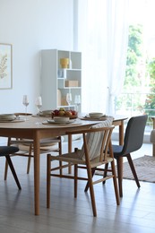 Photo of Beautiful table setting, chairs and decor in dining room. Interior design