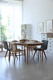 Photo of Beautiful table setting, chairs and decor in dining room. Interior design