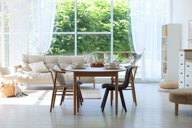 Photo of Beautiful table setting, chairs and decor in dining room. Interior design
