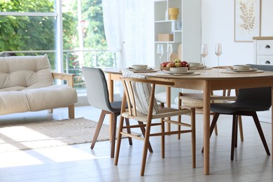 Photo of Beautiful table setting, chairs and decor in dining room. Interior design