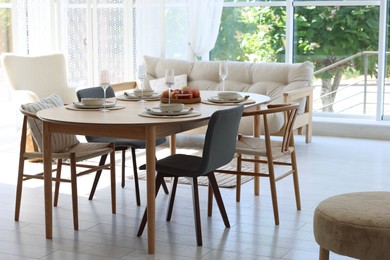 Photo of Beautiful table setting, chairs and decor in dining room. Interior design