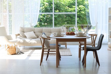 Photo of Beautiful table setting, chairs and decor in dining room. Interior design