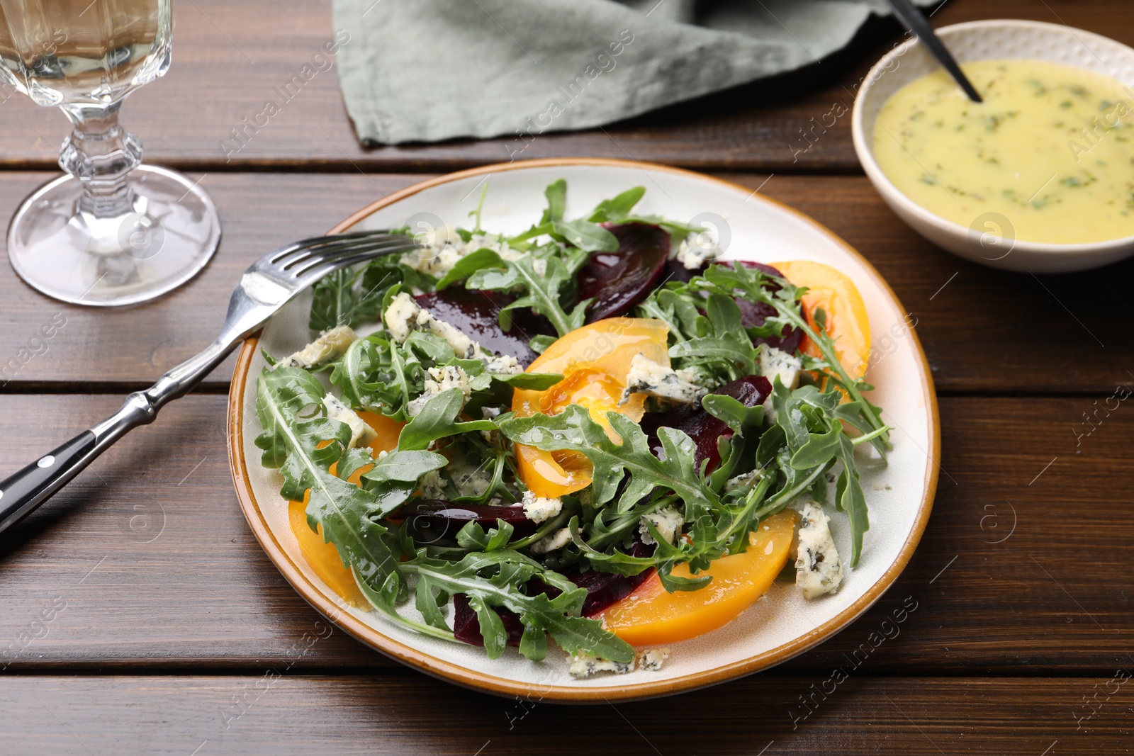 Tasty salad with arugula, blue cheese and vegetables on wooden table, closeup Photo of Tasty salad with arugula, blue cheese and vegetables on wooden table, closeup
