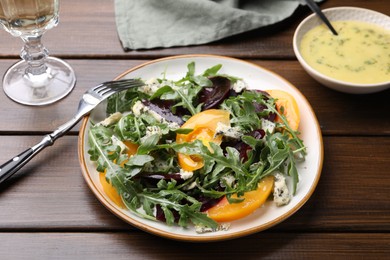 Photo of Tasty salad with arugula, blue cheese and vegetables on wooden table, closeup