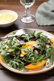 Photo of Tasty salad with arugula, blue cheese and vegetables on wooden table, closeup