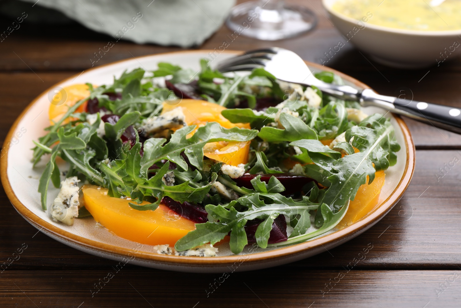 Tasty salad with arugula, blue cheese and vegetables on wooden table, closeup Photo of Tasty salad with arugula, blue cheese and vegetables on wooden table, closeup