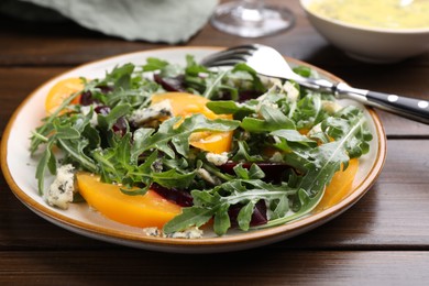 Photo of Tasty salad with arugula, blue cheese and vegetables on wooden table, closeup