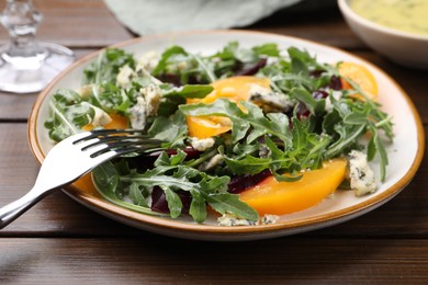 Photo of Tasty salad with arugula, blue cheese and vegetables on wooden table, closeup