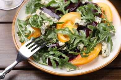 Photo of Tasty salad with arugula, blue cheese and vegetables on wooden table, closeup