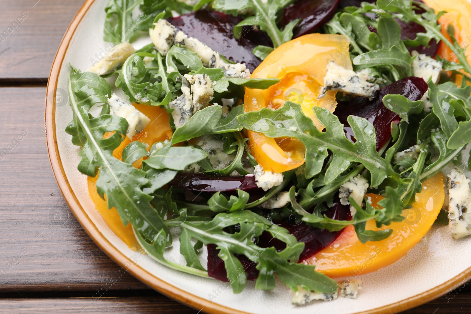 Tasty salad with arugula, blue cheese and vegetables on wooden table, closeup Photo of Tasty salad with arugula, blue cheese and vegetables on wooden table, closeup